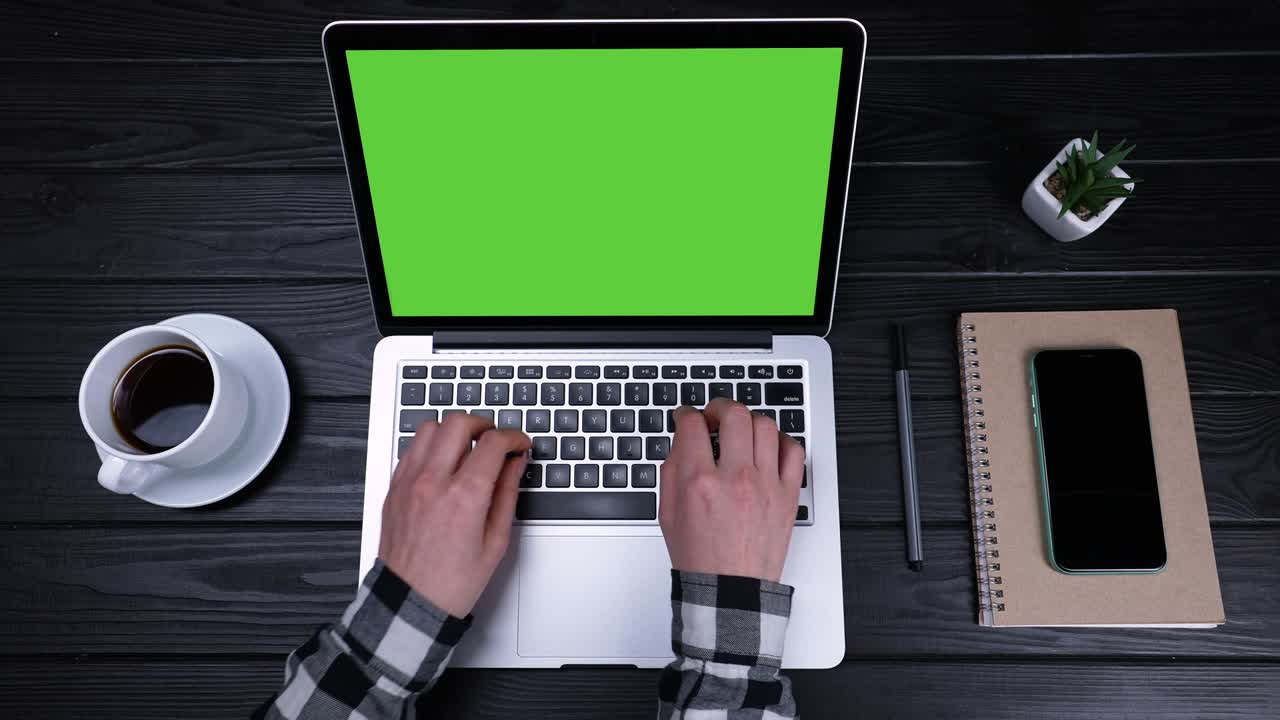 Girl's hands are typing on a green laptop screen in slow motion. View from above. Work from home, telework and selfisolation. Place a template for your text or image, advertising content. Close up