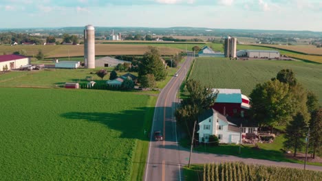 country road cuts through rural fields and farmland in america