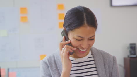 Geschäftsfrau,-Die-Im-Büro-Arbeitet-Und-Am-Schreibtisch-Steht-Und-Mit-Dem-Mobiltelefon-Spricht