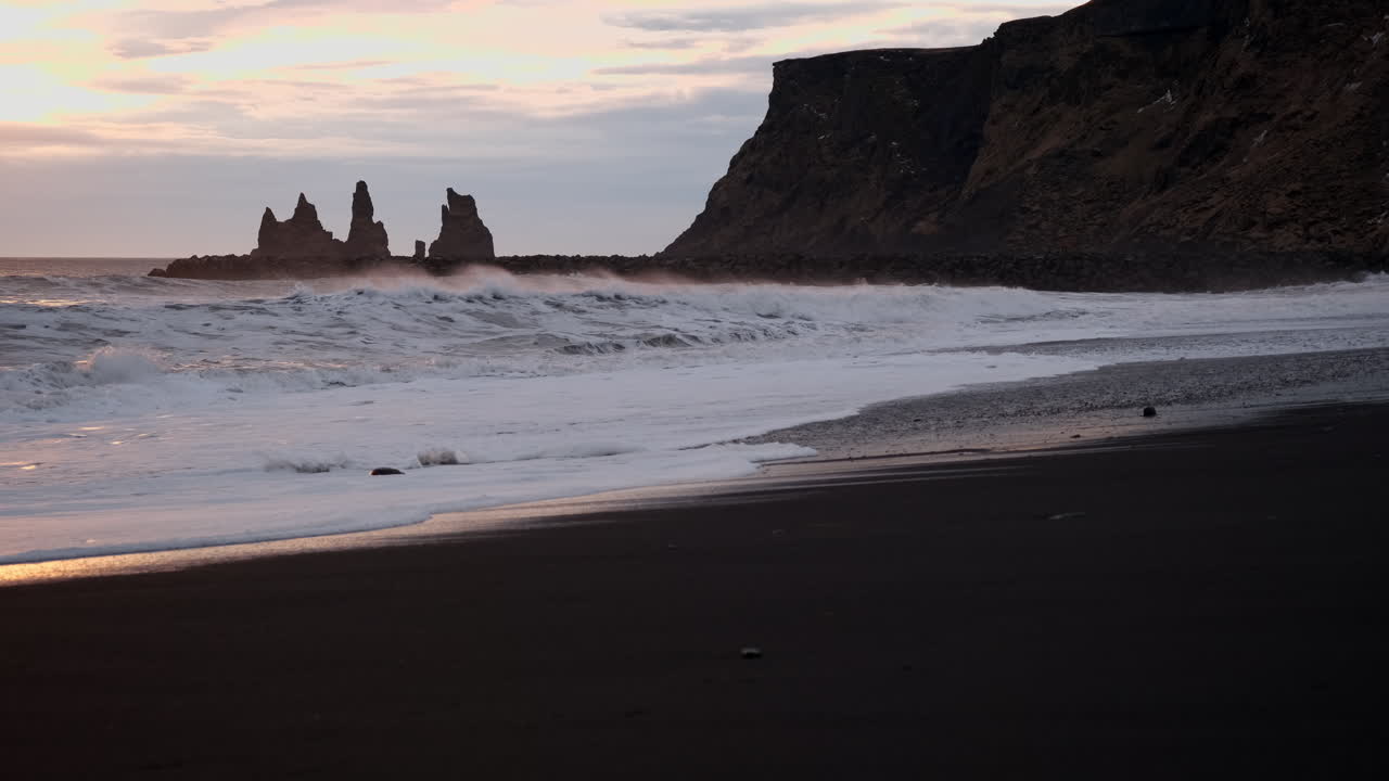 una icónica playa islandesa de arena negra en vik islandia al atardecer con olas rompiendo sobre arena negra