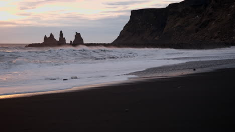 an iconic icelandic black sand beach in vik iceland at sunset with waves crashing over black sand