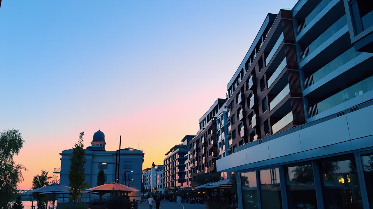 Bratislava, Slovakia - June 5, 2025: Sunset over modern waterfront buildings. Colorful sunset reflects on contemporary buildings along the waterfront promenade, creating a serene evening atmosphere