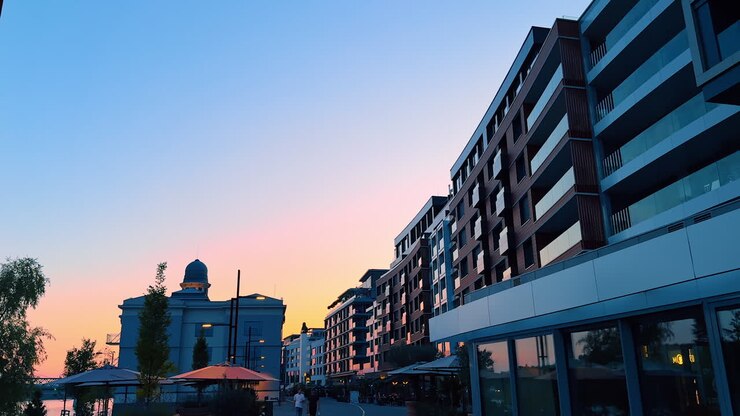 Bratislava, Slovacchia - 5 giugno 2025: Tramonto su edifici moderni sul lungomare. Un tramonto colorato si riflette su edifici contemporanei lungo la passeggiata sul lungomare, creando un'atmosfera serena serale.