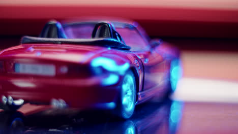 close-up of a red toy convertible car with neon reflections