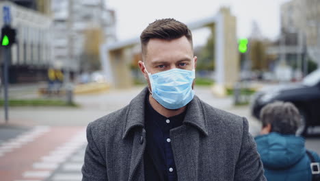 handsome man wearing a protective mask, walking in the city. male wearing a mask to prevent germs, toxic fumes, and dust. prevention of bacterial infection. corona virus pandemic.