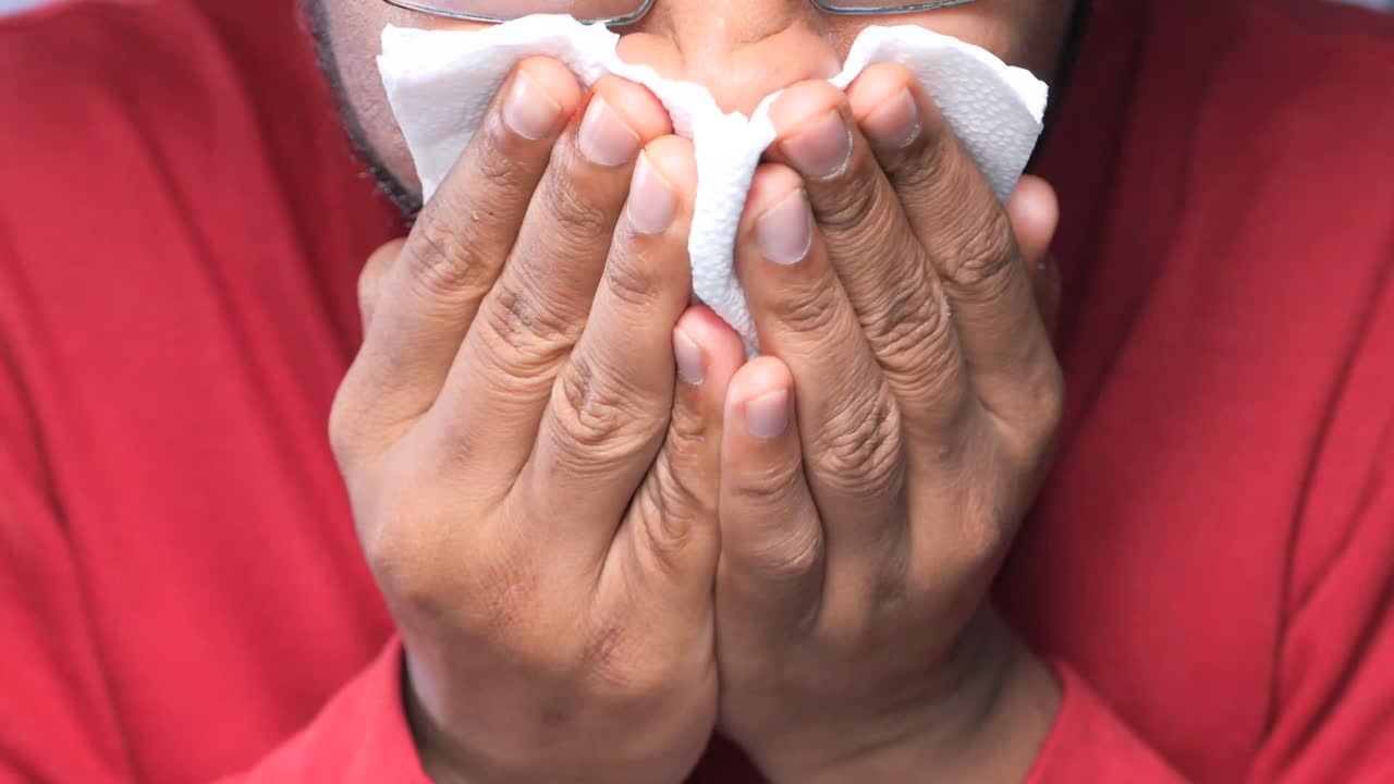persona que cubre la nariz y la boca con un pañuelo
