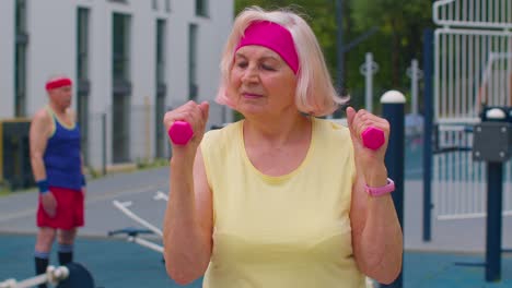mujer mayor madura abuela haciendo entrenamiento levantamiento de pesas ejercicio con pesas en el patio de recreo