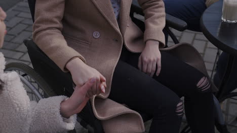 top view of young woman talking with her disable friend holding her hand in a bar terrace