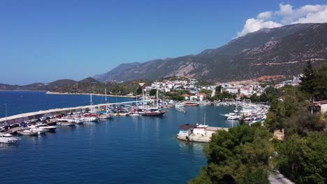 scenic view of kaş harbour with boats anchored below a mountainside village, capturing turkey’s mediterranean charm