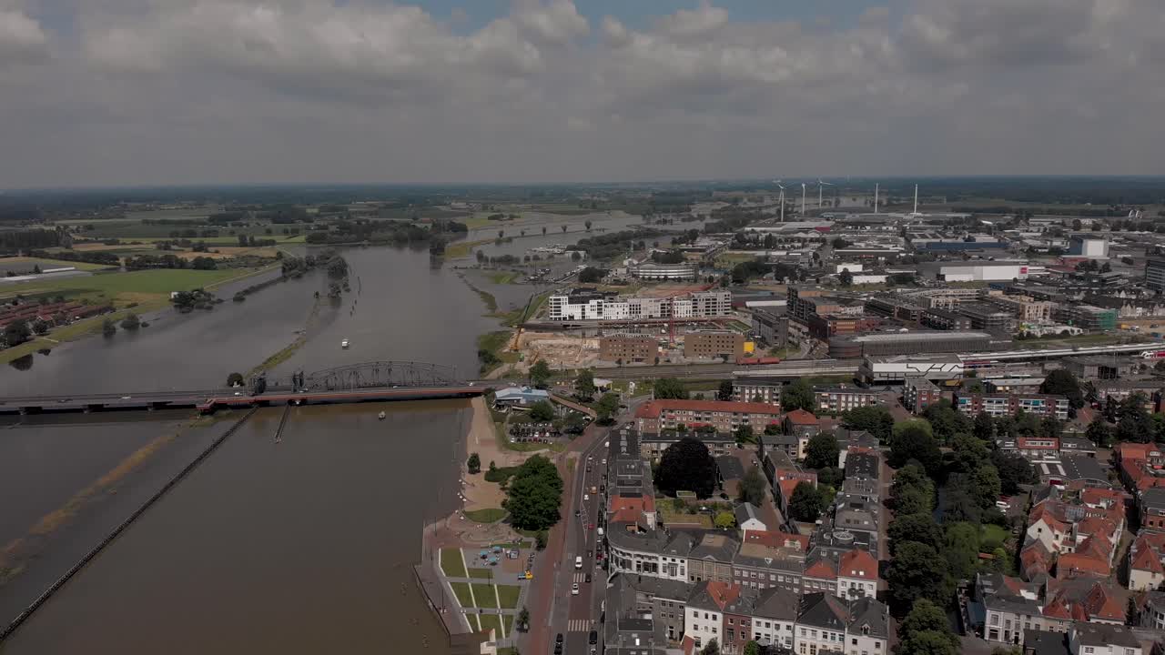 movimiento aéreo hacia atrás que muestra el paisaje urbano de zutphen, los países bajos, con el tráfico que pasa por el bulevar durante los altos niveles de agua del río ijssel con llanuras aluviales inundadas