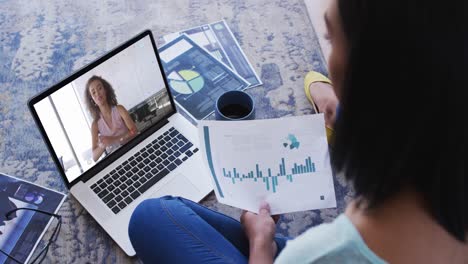 African-american-woman-holding-a-document-having-a-video-call-on-laptop-at-home