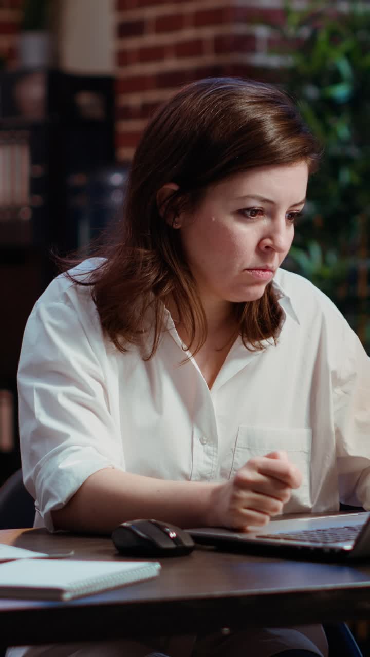 Vertical video Office clerk looking through financial business documents on laptop