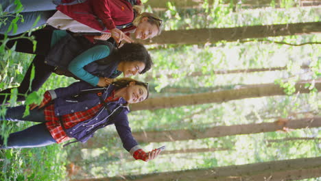 video vertical de amigas posando para selfies en el teléfono móvil en una caminata de vacaciones a través de los bosques