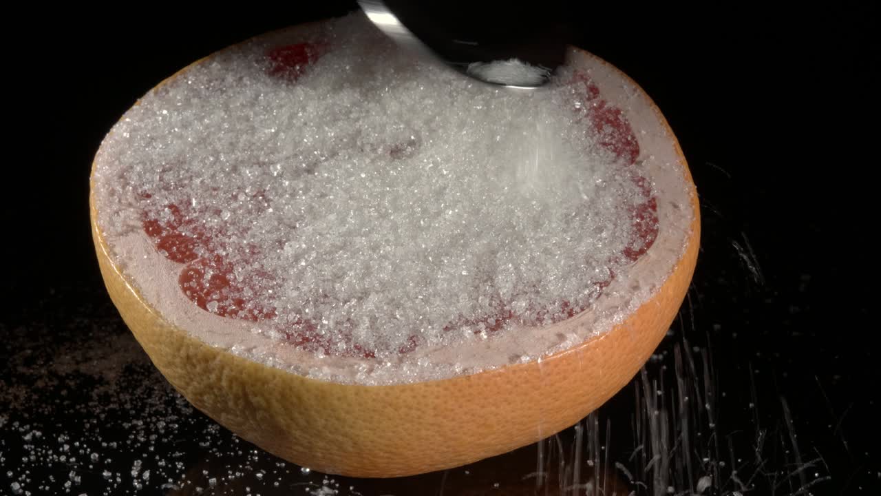 pomelo salpicado con azúcar. primer plano contra un fondo negro.