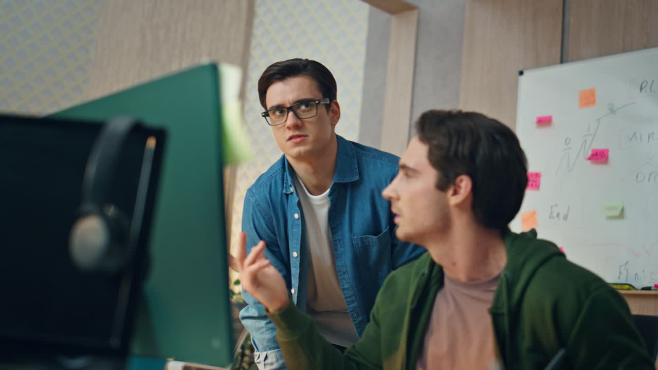 freelancers serios trabajando en computadora juntos en la oficina. hombre preguntando a su colega