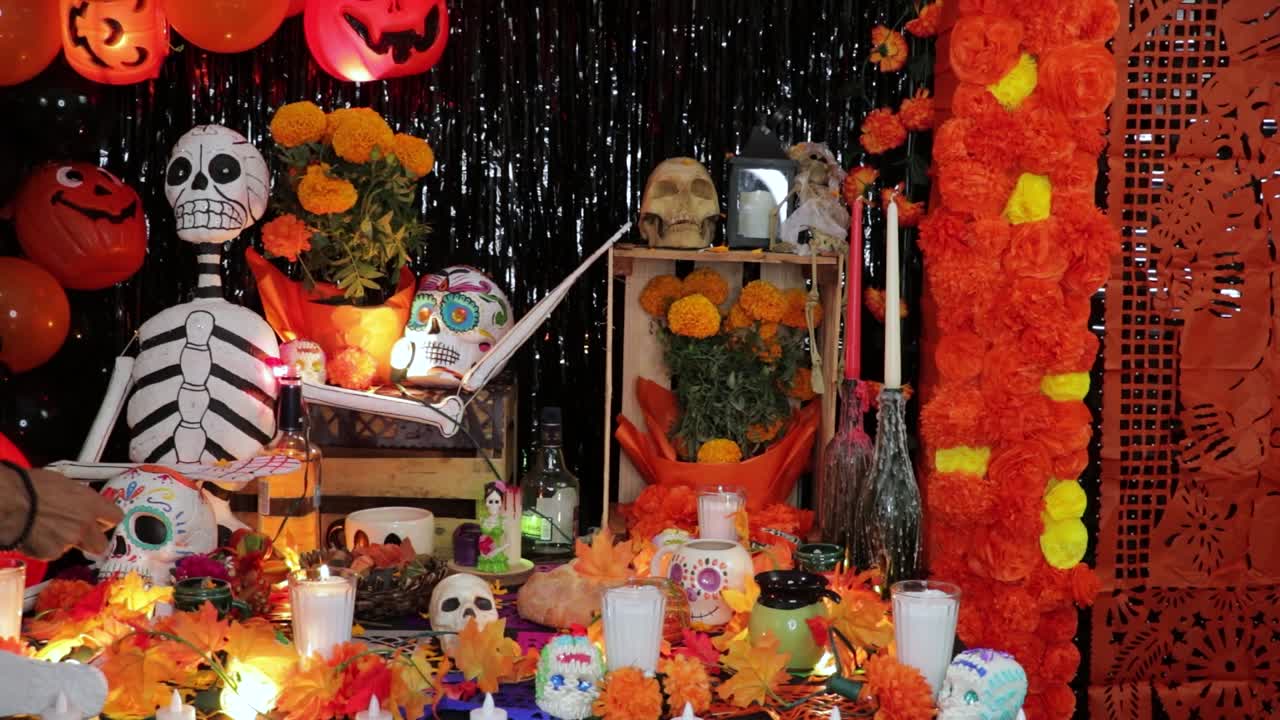 Latino man lighting candles for dead on decorated Día de Muertos altar.