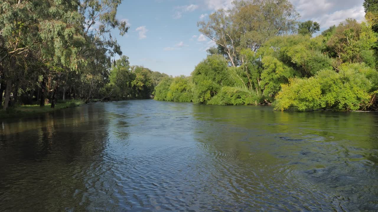 Wide view of the Tumut River with overhanging trees flowing strongly in the Snowy Mountain Region of Australia, New South Wales.