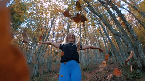 zoom en cámara superlenta de una mujer fitness que cae hojas de otoño en el bosque