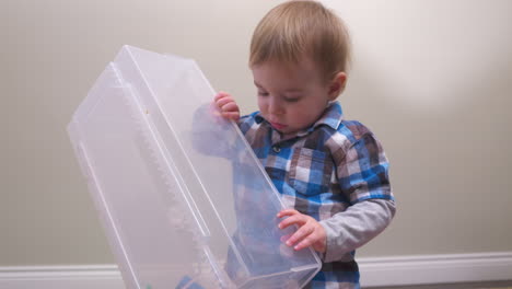 baby boy dumps his blocks out and puts the container on his head