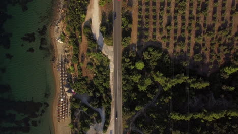 Vista-Aérea-De-La-Playa-Y-La-Carretera-Costera-Con-Tráfico-De-Automóviles-En-Grecia