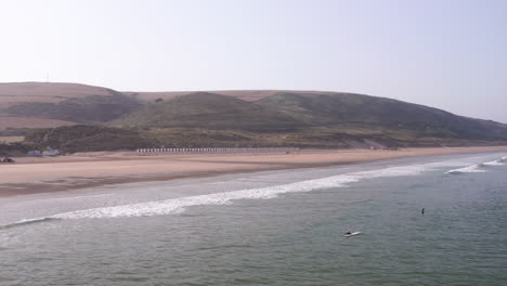 aerial shot pulling away from sandy north devon beach and tilting down to fade out