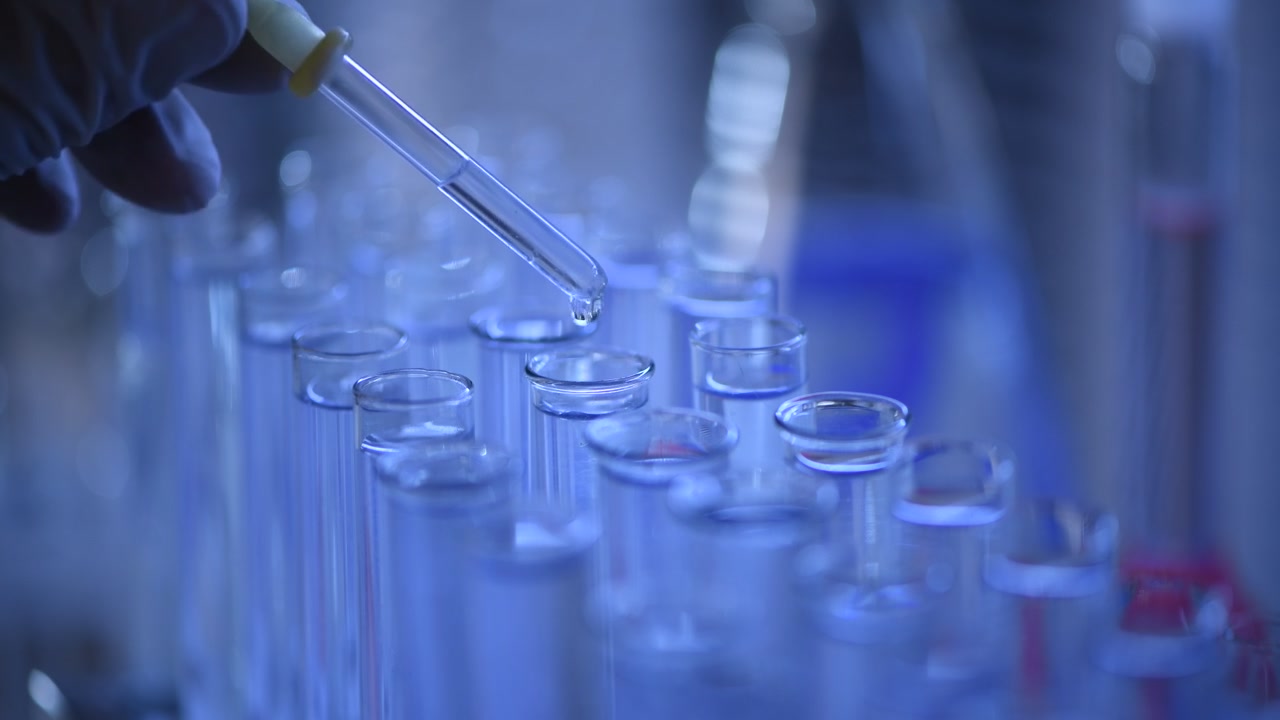 Close-up of Pipette Dropping Liquid into Laboratory Test Tubes