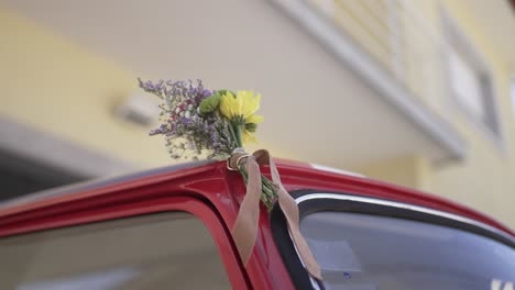 small wedding bouquet tied to classic red car door handle location irrelevant