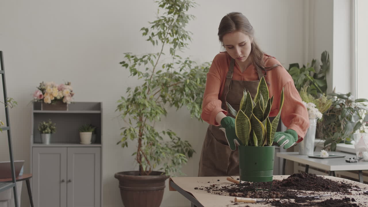 Donna che aggiunge terriccio a un vaso di fiori.