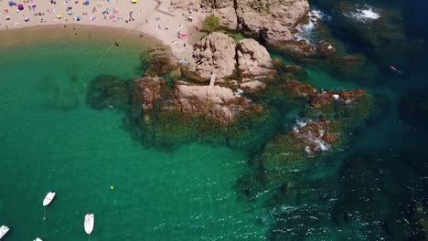 flying above the rocky coastline, next to a beach and a port of yachts on the mediterranean sea