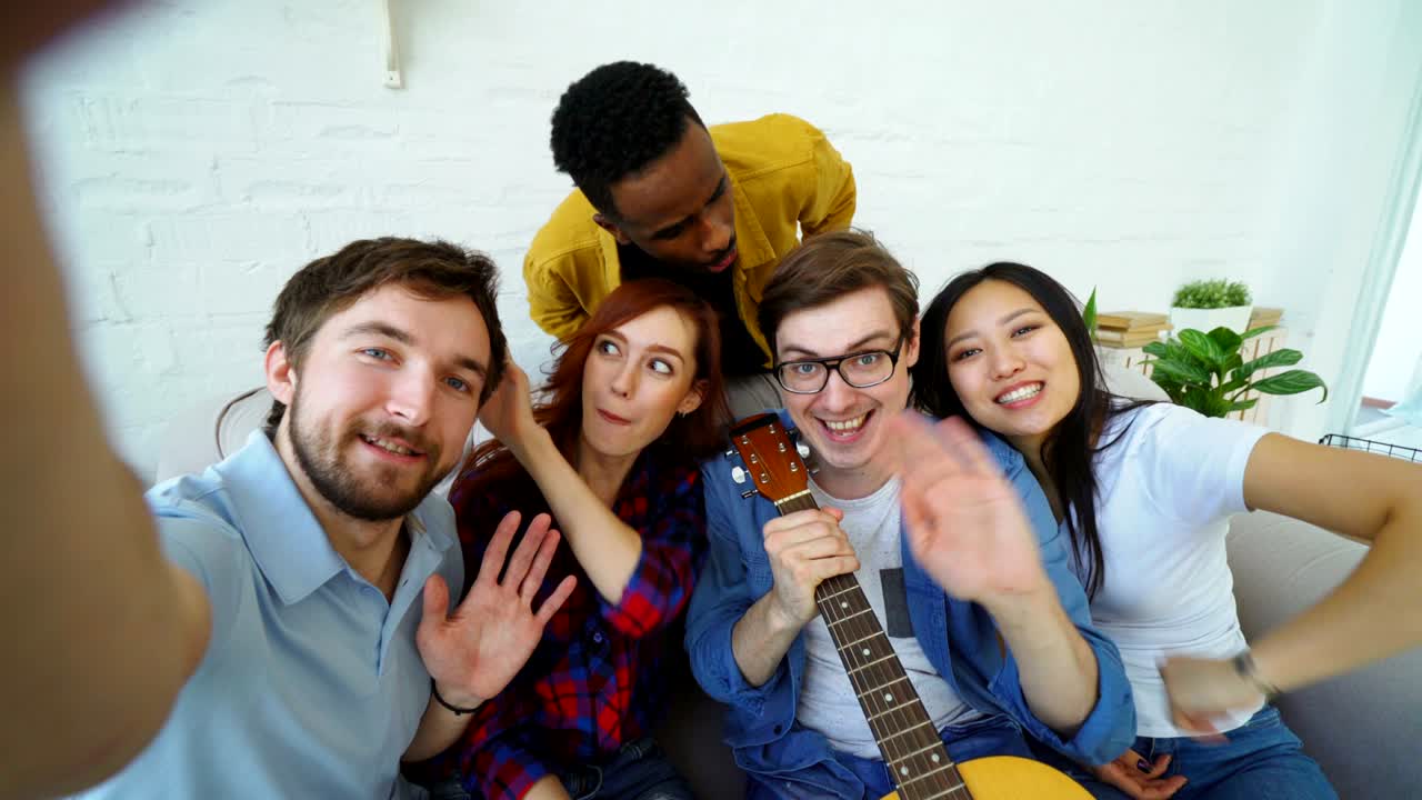 pov de un joven con amigos tomando fotos selfie con la cámara de su teléfono inteligente y divirtiéndose en casa en el interior