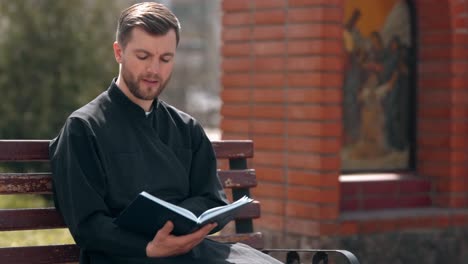 a handsome priest reads a prayer book and smiles happily