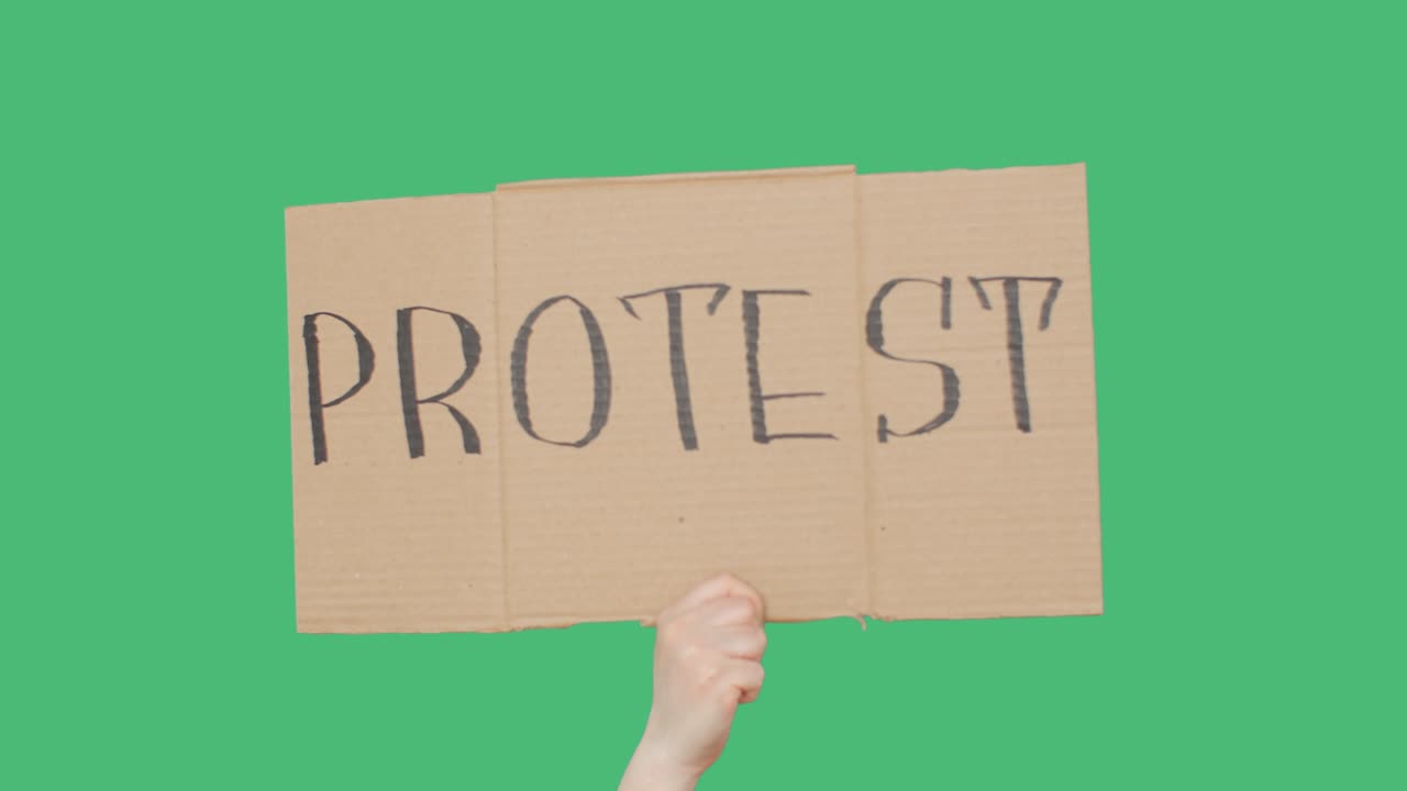 시위 표지판과 함께 손으로 카드보드, 녹색 chromakey 배경, 시위 카드보드 배너를 보여주는 손, 크로마 키 스크린 배경.