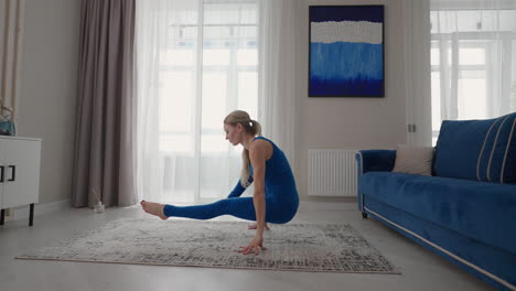 young woman is practising yoga at home relaxing in simple body position sitting on floor with beautiful furniture around. slim woman in sportswear standing on knees bending back and doing camel pose