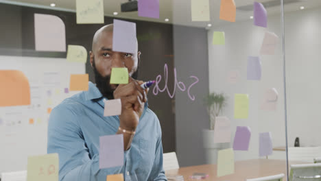 african american businessman brainstorming, making notes on glass wall in office in slow motion