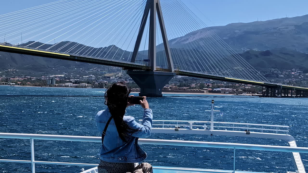 hermosa dama tomando fotos del puente del río desde un buque en movimiento, vista trasera