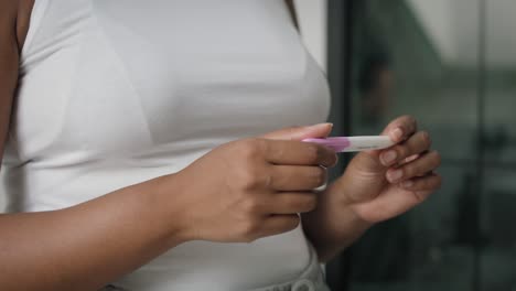 detalle de las manos de una mujer afroamericana irreconocible estresada esperando los resultados de la prueba de embarazo.