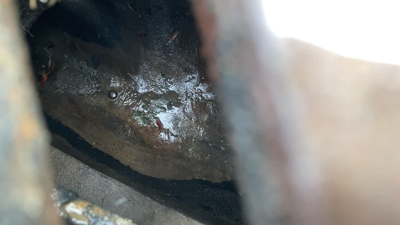 el agua corre hacia un drenaje pluvial de la tapa de la alcantarilla en una calle de la ciudad 1