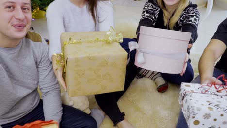 jóvenes felices dan regalos de navidad a la cámara