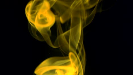 el humo amarillo se eleva lentamente con gracia hacia arriba. el humo de color sopla de abajo hacia arriba. primer plano, aislado sobre un fondo negro