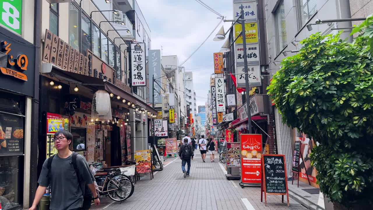Bustling Japanese shopping street lined with colorful signs and stores on a cloudy day