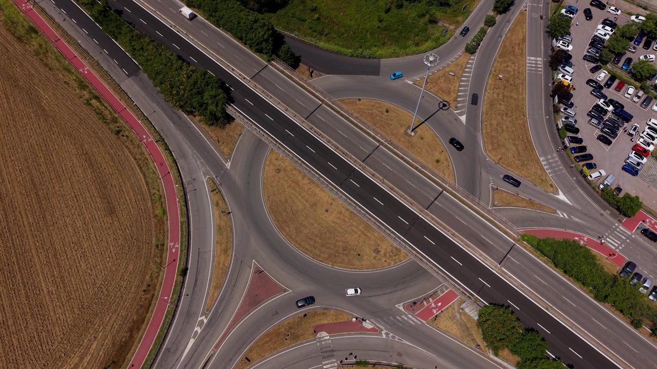 Aerial view of a roundabout intersection on the outskirts of Milan during summer, showing road infrastructure and suburban transportation networks.