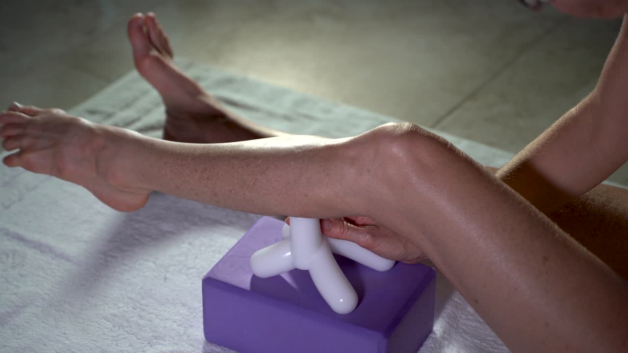 Primo piano di una donna matura che utilizza un attrezzo da massaggio per allungare i muscoli del polpaccio
