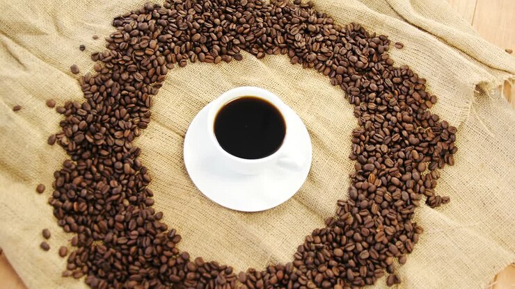 Tazza di caffè circondata da chicchi tostati