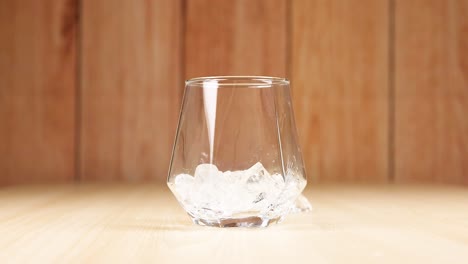 cubos de hielo cayendo en un vaso vacío