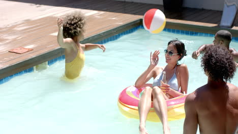 relaxing in pool, diverse friends playing with beach ball and enjoying summer day