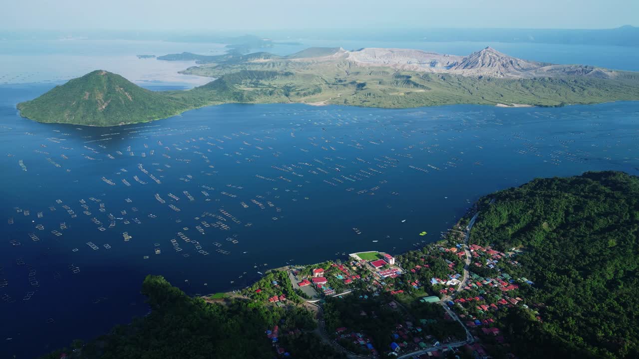 Denní letecký pohled z vyhlídky Binintiang Malaki Western Viewpoint zachycující sopku Taal, kráter, jezero Taal, Agoncillo Baywalk a čtvercové rybníky s malými čluny v jednom panoramatickém záběru