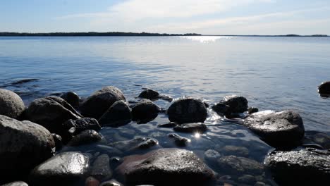 calm lake scenery with rocks on coast and water waving smoothly