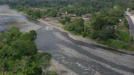 trucks crossing bridge under construction over river affected by drought in san jose, costa rica, aerial pan left reveal shot