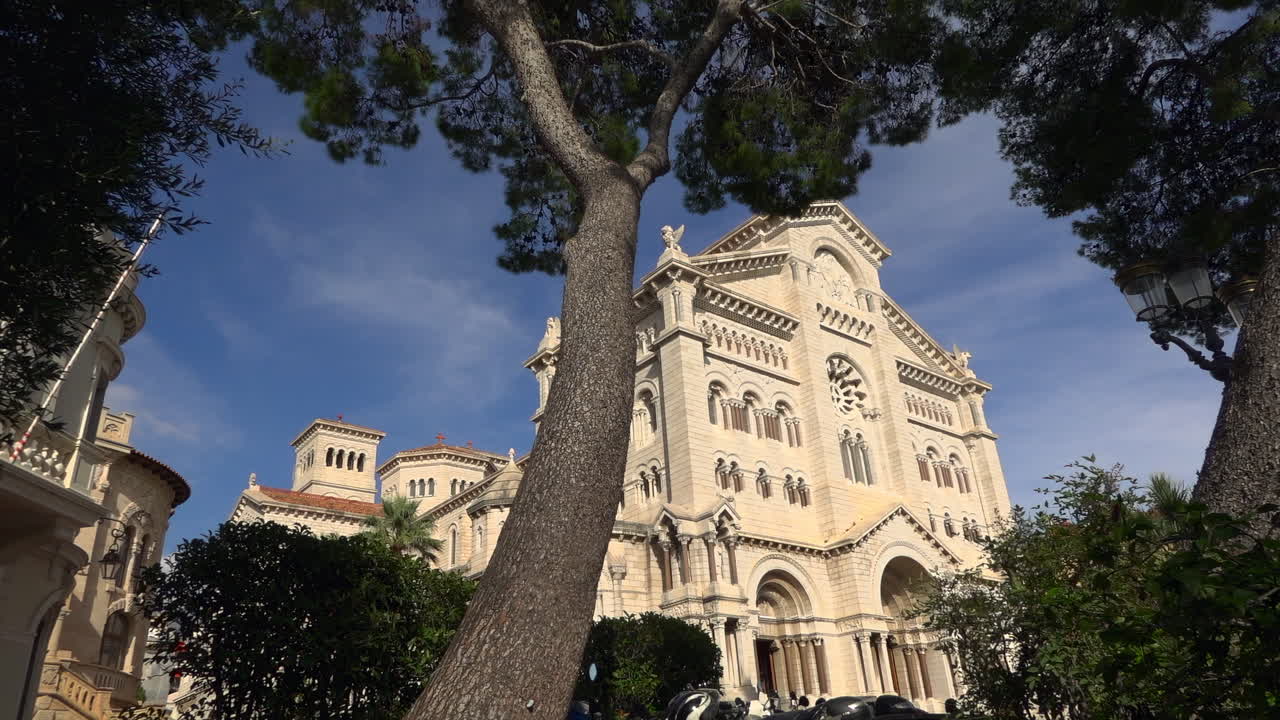 Monaco City, Monaco – 4. juli 2025: Lav vinkel af facaden på Vor Frue af den Ubesmittede Undfangelses Katedral, indrammet af grønne træer
