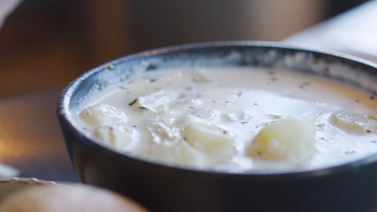 Close-up of spoon serving steaming Cullen skink soup with potatoes and leeks in cozy lighting